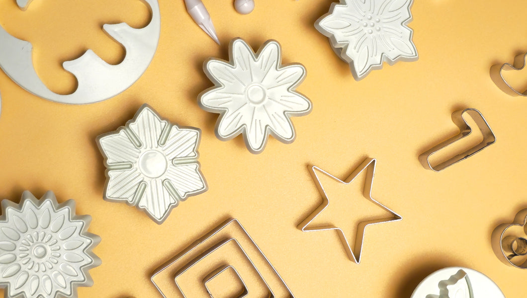 Collection of various metal cookie cutters on a yellow background