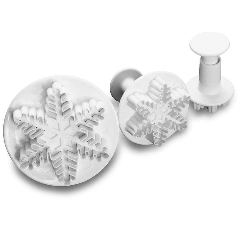 Set of three snowflake-shaped fondant cutters on a white background