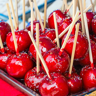 Red candy apples on sticks displayed in a tray